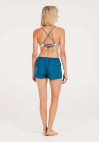 Il set di costumi da bagno presenta un reggiseno con pattern multicolore e spalline a X, accompagnato da un paio di pantaloni corti azzurri con vita elastica. Texture liscia.