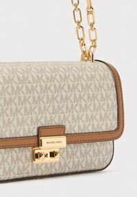 Borsa marrone e beige con motivo a logo "MK" ripetuto, dettagli in metallo color oro, chiusura con lucchetto e tracolla a catena. Materiale testurizzato.