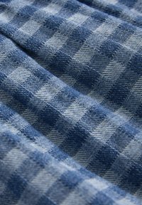 Sininen ruudullinen kangas, jossa on vuorotellen vaaleita ja tummia neliöitä. Teksturoitu kudos, pehmeä pinta ja hieman rypistyneet ilmeet.