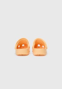 Orange plastic clogs with open backs, rounded edges, textured inner soles, and ventilation holes on the sides.