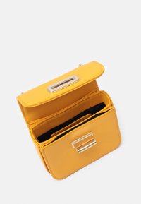 Żółty skórzany portfel z metalowym zapięciem. Wewnątrz znajduje się wiele przegródek na karty oraz teksturowane wykończenie. Kompaktowy prostokątny kształt.