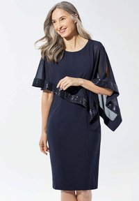Navy Kleid mit einem fließenden Chiffonüberwurf und Paillettenverzierung. Verfügt über einen runden Ausschnitt und kurze Ärmel. Glatter Stoff, knielang.