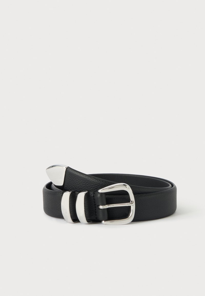 Ceinture en cuir noir roulée avec une boucle en métal argenté, deux passants assortis et une pointe métallique pointue sur un fond uni.