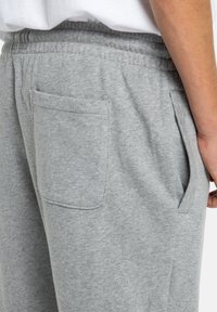 Hellgraue Sweatpants aus einem weichen Baumwollmix. Mit elastischem Bund, Seitentaschen und einer einzelnen Gesäßtasche. Einfaches Design.