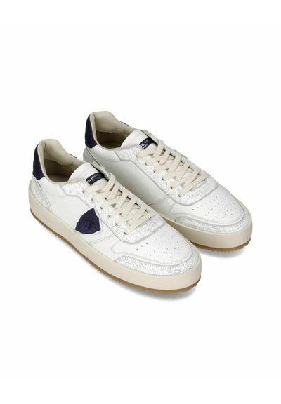 Baskets en cuir blanc avec des accents bleu marine, superpositions texturées, bout perforé et semelle en caoutchouc beige. Présente un design à lacets et un col rembourré.