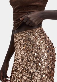 Pants med paillet-udsmykning, der har en tæt silhuet, metalbronzefarve, glat tekstur og en bred talje.