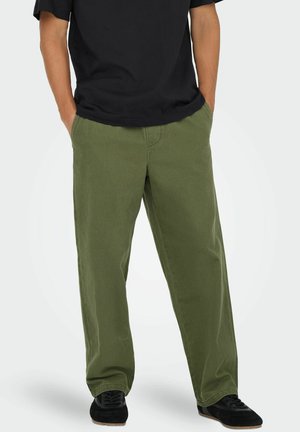 Green cotton pants with a relaxed fit, featuring side pockets and a straight leg design. Paired with a black t-shirt and black shoes.