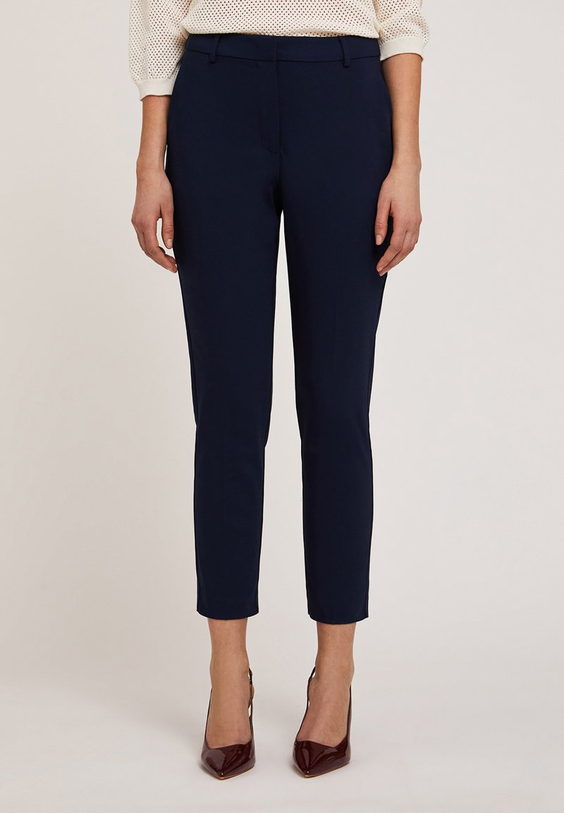 Navy blauwe op maat gemaakte broek met een slim fit, met een gladde textuur, middelhoge taille en geplooide details. Gecombineerd met glanzende bordeauxrode hakken.