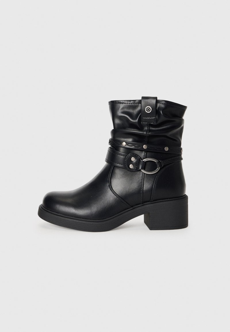 Botte en cuir noire mi-mollet avec talon carré bas, boucle décorative et détails de sangles, et un petit emblème de logo près du haut.
