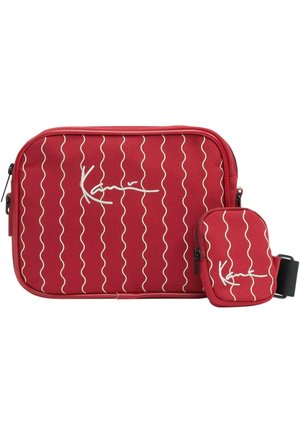 Red fabric bag with white wave pattern and signature logo. Includes a smaller pouch attached by a strap for added storage convenience.