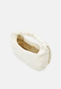 Bolso de tela blanca con un asa fruncida, forma redondeada y cierre a presión dorado. El interior está forrado con un material marrón.