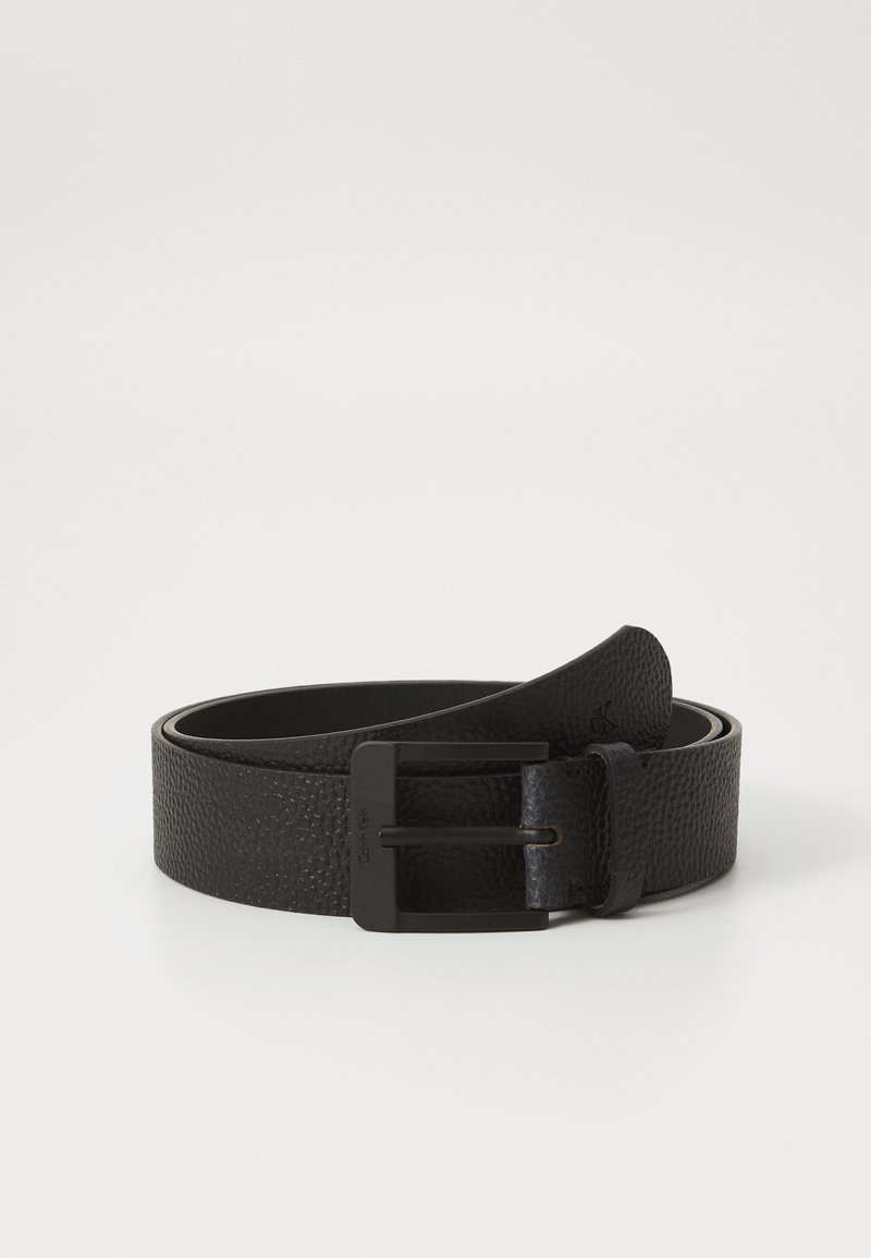Cinturón de cuero negro con un acabado texturizado, que cuenta con una hebilla de metal negro mate. Bordes suaves y un diseño minimalista.