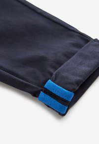 Tela azul marino oscuro con un borde doblado asegurado con una correa de velcro azul sobre un fondo blanco.