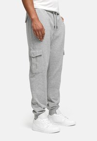 Gray cargo joggers in a soft fabric, featuring side pockets and a relaxed fit, with elastic cuffs. Paired with white sneakers.