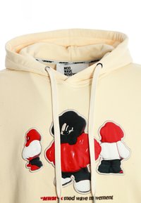Sudadera crema con tres personajes tipo caricatura en rojo, blanco y negro en la parte frontal, y el texto "movimiento mod wave" debajo del diseño.