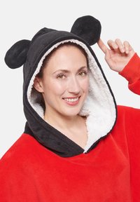 Felpa oversized rossa in pile con cappuccio a forma di orecchie di orso nere. Foderata con materiale bianco morbido. Presenta una grande apertura frontale e una vestibilità comoda.