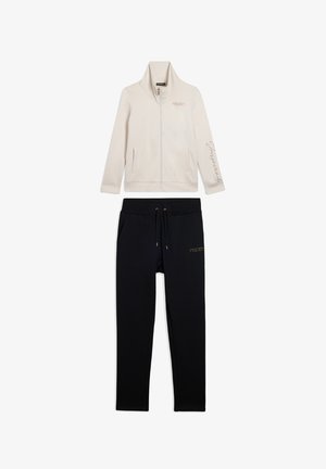 Giacca a zip crema con logo "FREDDY" e scritta sulla manica, abbinata a pantaloni neri con coulisse e logo "FREDDY" sulla coscia.