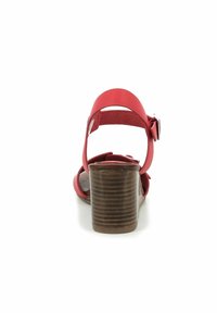 Sandalia roja de tacón con un bloque de madera apilado y una correa en el tobillo asegurada con un hebilla lateral, vista desde atrás.