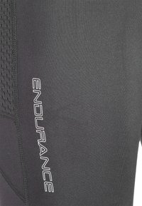 Svart atletisk tyg med strukturerad sidopanel och vit vertikal "ENDURANCE"-logotyp tryckt på den släta delen.