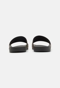 Sorte svart sandaler med glatt, matt finish, åpen bakdesign og teksturert såle forgrep. Lett og fleksibelt materiale.
