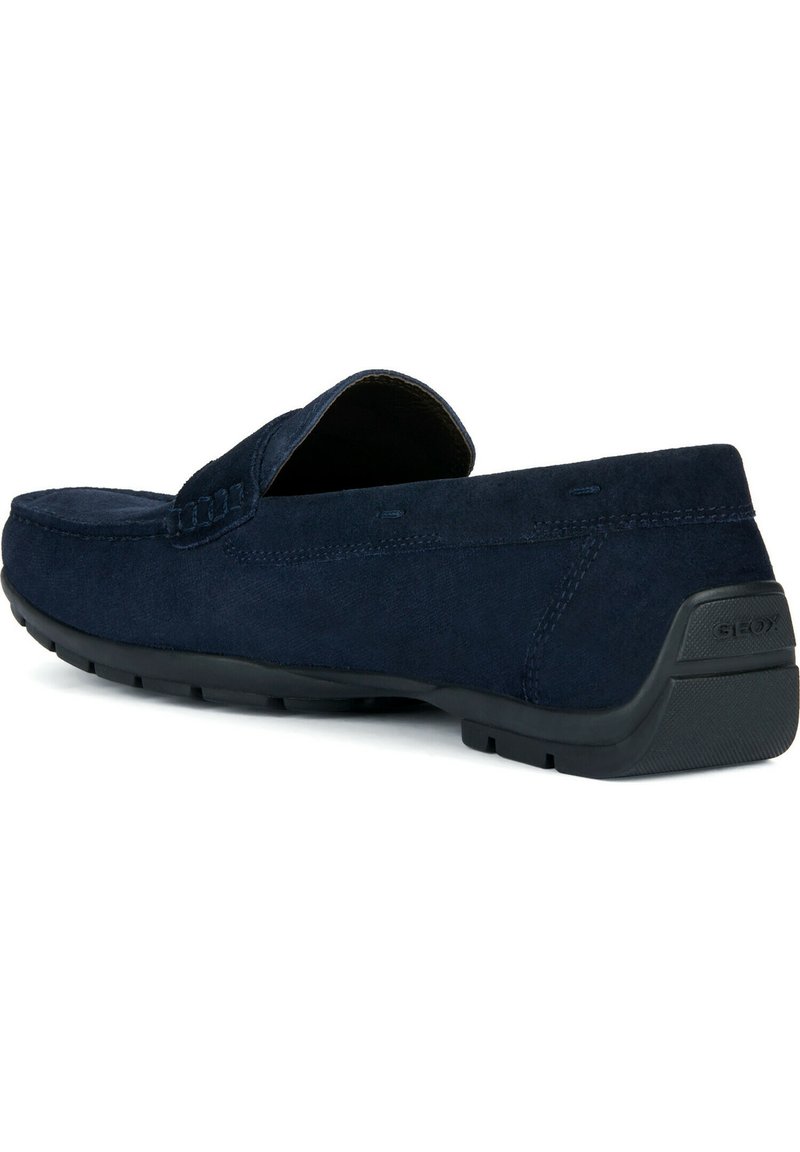 Mocassin en suède bleu marine avec semelle en caoutchouc noir, détails cousus et un petit talon, marqué "GEOX" à l'arrière.