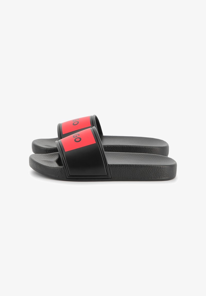 Black slide sandals with a textured surface, featuring wide red straps with black branding. The overall design is simple and flat.