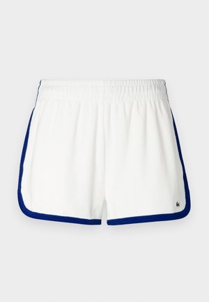 Shorts en tissu éponge blanc avec des accents bleu marine, taille élastiquée et ourlets arrondis. Présente un logo sur le bas à droite.
