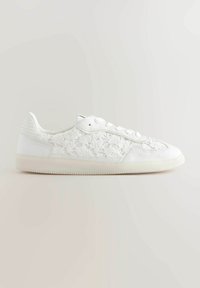 Sneaker bianco con dettagli in pizzo sui lati, tessuto testurizzato e suola in gomma. Punta arrotondata e chiusura tradizionale con lacci.
