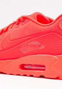 Nike Air Max tenisky v jasně neonově růžové barvě, s prodyšnou síťovinou, texturovaným povrchem, vyčnívajícím logem a viditelným vzduchovým polstrováním.