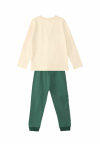 Weißes Langarmshirt über dunkelgrünen Hosen mit gerippten Bündchen; die Hose hat eine Seitentasche und eine glatte Textur.