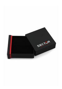 Scatola regalo nera con una texture liscia, caratterizzata da una fascia accentata rossa. Il coperchio è parzialmente aperto, mostrando un interno nero e il logo "SECTOR NO LIMITS".