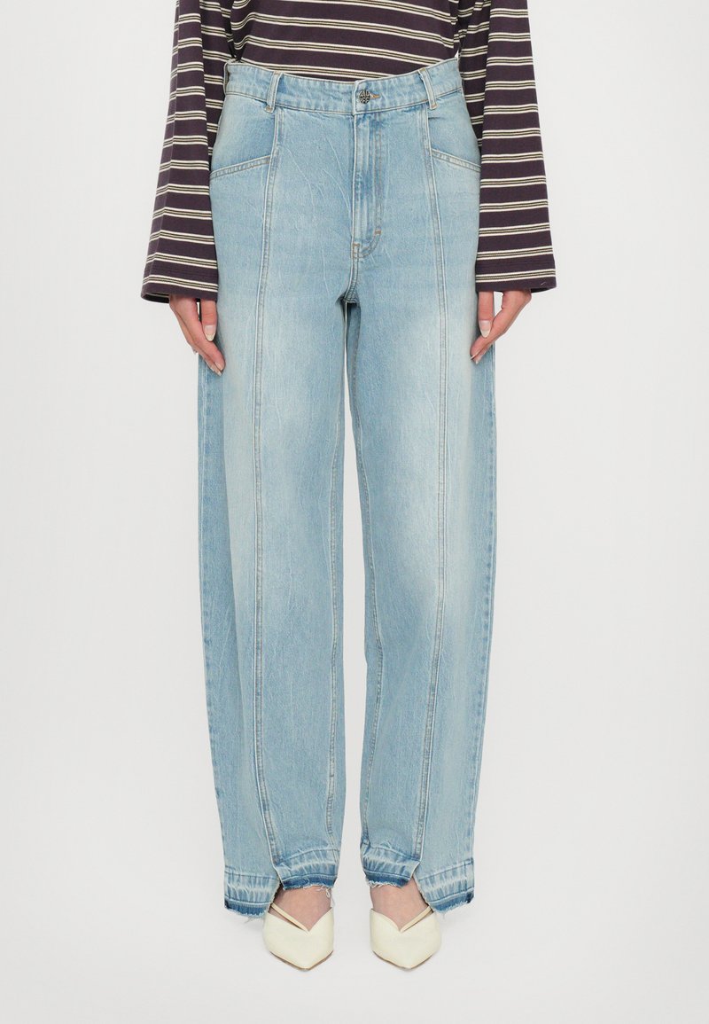 Lysblå vide jeans med høj talje, der har forlommer og rå kant. Sammen med cremefarvede spidse sko.