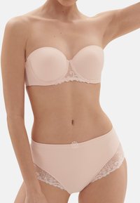 Reggiseno senza spalline di colore rosa pallido con tessuto morbido e dettagli in pizzo. Le mutandine a vita alta coordinate presentano accenti di pizzo floreale e accessori a forma di fiocco.