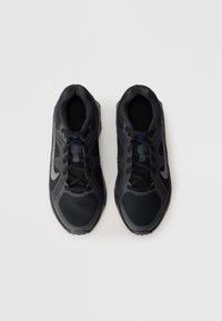 Ténis atléticos pretos com parte superior em malha, design texturizado, atacadores pretos e um detalhe prateado do logótipo do lado. Sola plana de borracha.