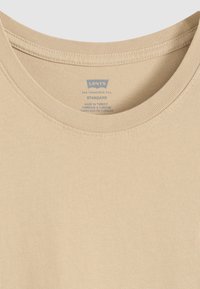 Beige cotton t-shirt with a round neckline and ribbed details. The label indicates "Levi's" and care instructions printed in blue.