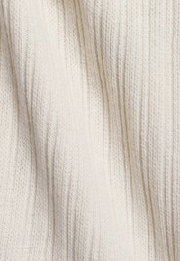 Rippstrickstoff in Off-White, mit einer sanften Textur, ausgeprägten vertikalen Linien und einer leicht unregelmäßigen Oberfläche.