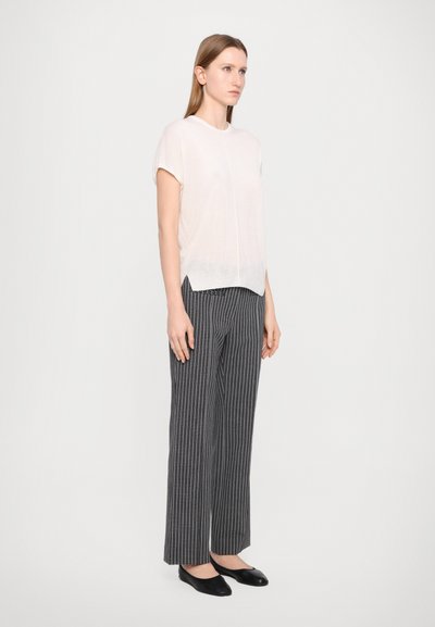Light pink short-sleeve top with a round neckline, paired with black and white checkered wide-leg trousers and black flats.