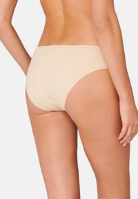Beige sömlös bikiniunderdel med mjuk textur, måttlig täckning och en enkel, minimalistisk design. Inga synliga sömmar eller mönster.