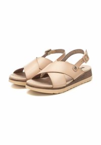Sandali beige con design a tracolla incrociata, realizzati in morbida pelle, suola in gomma e cinturino slingback con dettagli a fibbia metallica.