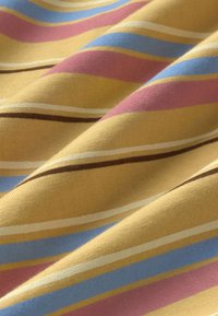 Tissu doux à rayures diagonales en jaune moutarde, rose, bleu clair, blanc et marron, présentant des pliures légères et une texture délicate.