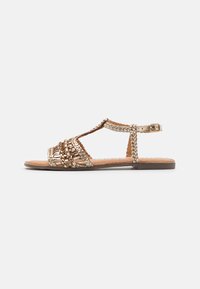 Sanda roja plana de oro y beige con diseño de tira en T, hebilla ajustable en el tobillo y superficie texturizada. Suela plana con detalles minimalistas.
