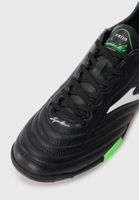 Mustad nahast spordijalatsid mustade paeltega, valgete ja roheliste aktsentidega, bränditud "Joma Aguila" keele ja varvaste piirkonnas.