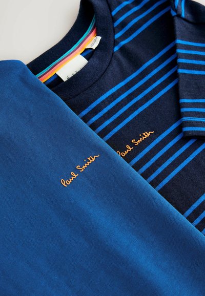 Du matiniai marškinėliai: viena vientisa mėlyna ir viena tamsiai mėlyna su mėlynomis juostelėmis. Abu turi "Paul Smith" logotipą oranžiniais siūlais. Minkšta medvilnė.