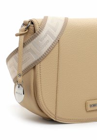 Sac à épaule en simili cuir beige avec une surface texturée, comportant une bandoulière décorative à motifs et une étiquette logo argentée.