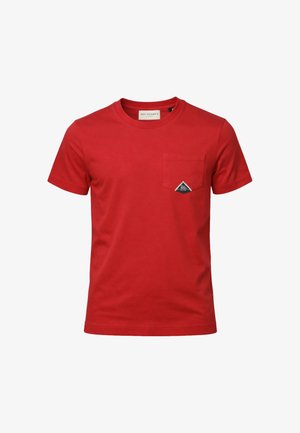 Maglietta rossa a maniche corte con scollo a girocollo e taschino sul petto con una piccola toppa triangolare in bianco e nero con logo.