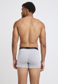 Grey boxer shorts with a black logo waistband, featuring a snug fit and smooth texture, viewed from the back on a bare torso.