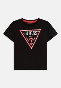 T-shirt noir à manches courtes avec un grand logo triangulaire rouge et blanc comportant le texte "GUESS®" et "U.S.A." au centre. Tissu en coton doux.