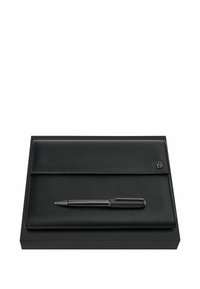 Portefeuille en cuir noir avec un emblème en métal et un stylo noir assorti posé dessus, tous deux placés sur une boîte rectangulaire noire.
