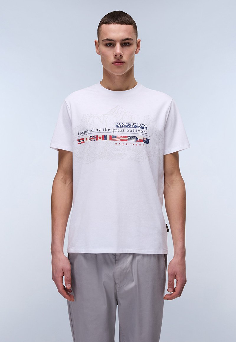 Camiseta de algodón blanca con un diseño gráfico que presenta banderas e imágenes de montañas. El texto dice "Inspirado por la naturaleza".