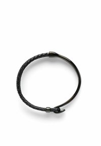 Svart läderarmband med flätad design och en glänsande metallspänne och accent, som visar en slät, texturerad yta.